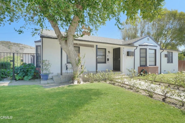 ranch-style house featuring covered porch, a front lawn, fence, and stucco siding