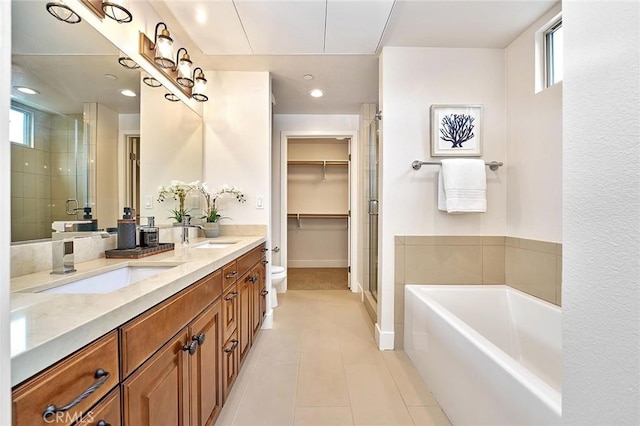 full bathroom featuring a stall shower, tile patterned flooring, a sink, and a garden tub