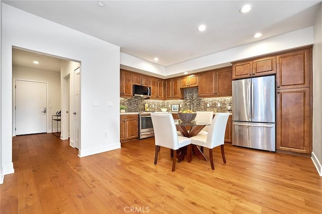 kitchen with tasteful backsplash, appliances with stainless steel finishes, light wood-type flooring, a kitchen bar, and recessed lighting