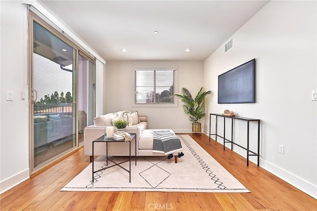 living area with recessed lighting, visible vents, baseboards, and wood finished floors