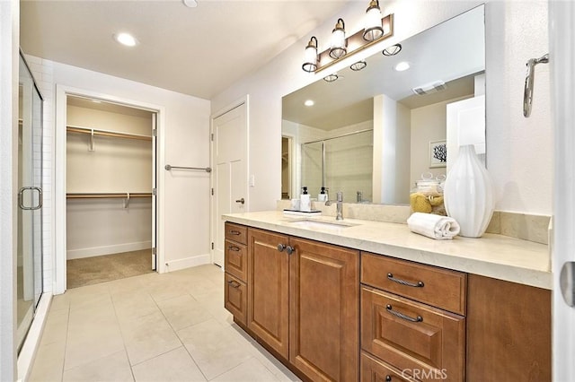 bathroom featuring a stall shower, visible vents, tile patterned floors, a walk in closet, and vanity