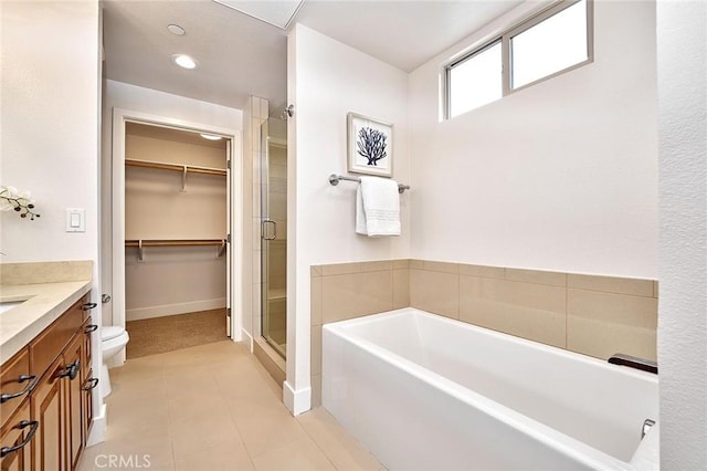 bathroom with a garden tub, vanity, a shower stall, tile patterned floors, and a walk in closet