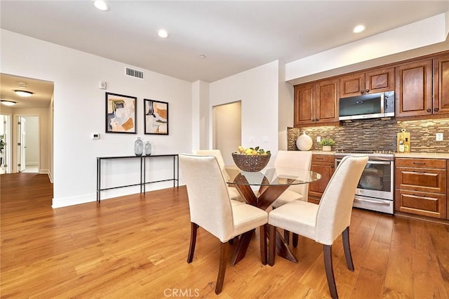 dining space featuring baseboards, light wood-style flooring, visible vents, and recessed lighting