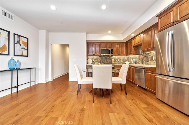 kitchen featuring light countertops, visible vents, backsplash, appliances with stainless steel finishes, and light wood-style floors