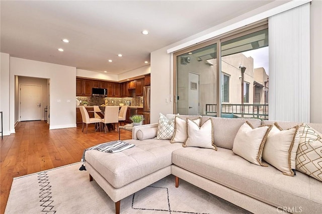 living room featuring recessed lighting, baseboards, and light wood finished floors