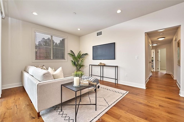 living room with baseboards, light wood-type flooring, visible vents, and recessed lighting