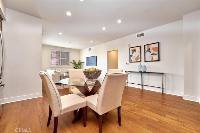 dining room featuring baseboards, light wood-type flooring, visible vents, and recessed lighting