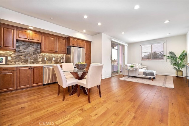 kitchen with recessed lighting, light countertops, appliances with stainless steel finishes, light wood-type flooring, and backsplash