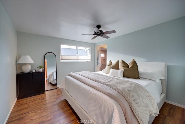 bedroom with a ceiling fan, baseboards, and wood finished floors