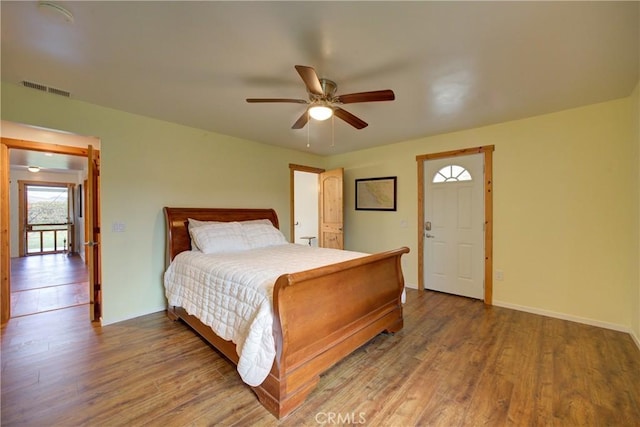 bedroom with ceiling fan, wood finished floors, visible vents, and baseboards