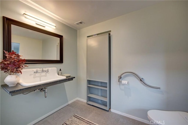 half bath with toilet, visible vents, baseboards, and a sink