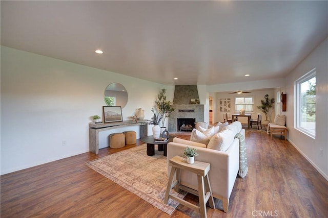 living room with dark wood-type flooring, recessed lighting, a fireplace, and baseboards