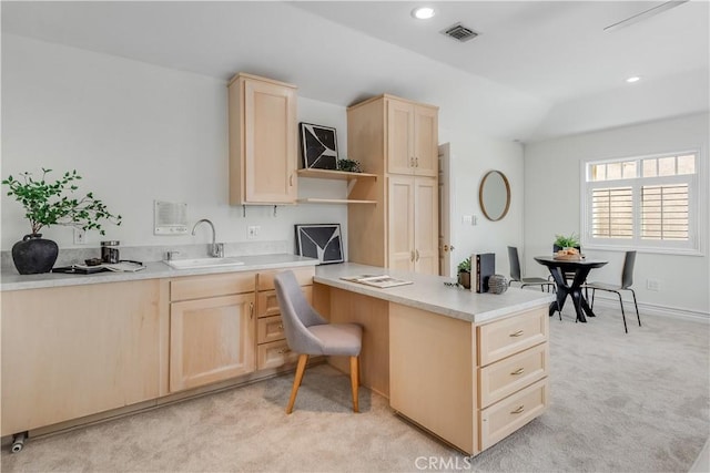 kitchen with visible vents, light colored carpet, a peninsula, light brown cabinets, and a sink