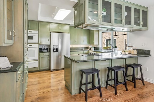 kitchen featuring dark countertops, light wood-style flooring, green cabinetry, a peninsula, and stainless steel fridge with ice dispenser