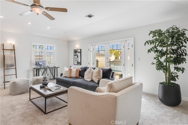 living room featuring baseboards, a healthy amount of sunlight, visible vents, and light colored carpet