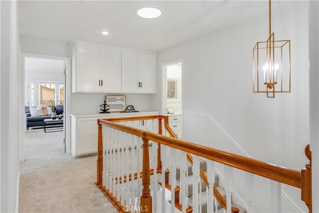 hall with recessed lighting, light colored carpet, a notable chandelier, and an upstairs landing