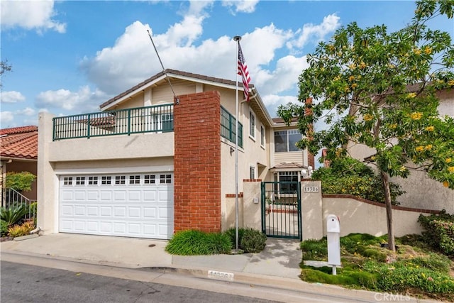 view of front of house featuring driveway, a garage, a balcony, a gate, and stucco siding