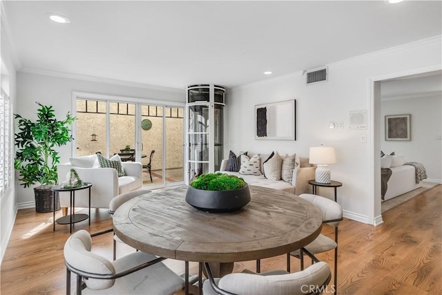 dining space with light wood-style floors, visible vents, crown molding, and baseboards