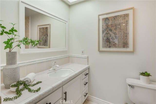 half bath featuring toilet, decorative backsplash, vanity, and baseboards