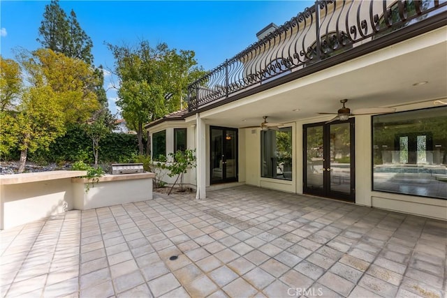 view of patio with exterior kitchen, french doors, a balcony, and a ceiling fan