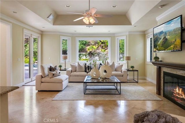 living area with a tray ceiling, a glass covered fireplace, plenty of natural light, and visible vents