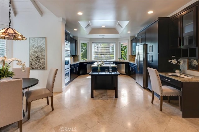 kitchen featuring stainless steel appliances, dark cabinetry, a raised ceiling, and recessed lighting