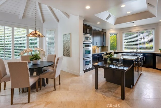 kitchen featuring baseboards, a raised ceiling, appliances with stainless steel finishes, backsplash, and a sink