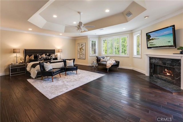 bedroom featuring a premium fireplace, visible vents, baseboards, dark wood-style floors, and a raised ceiling