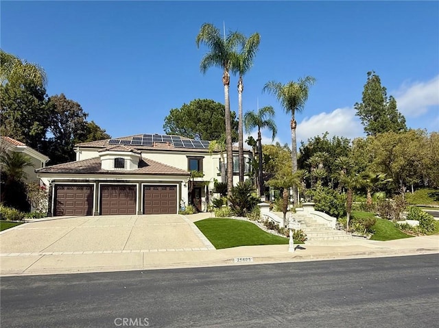 view of front of house with an attached garage, solar panels, concrete driveway, and stucco siding