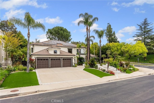 view of front of home with concrete driveway, a tiled roof, an attached garage, stucco siding, and solar panels