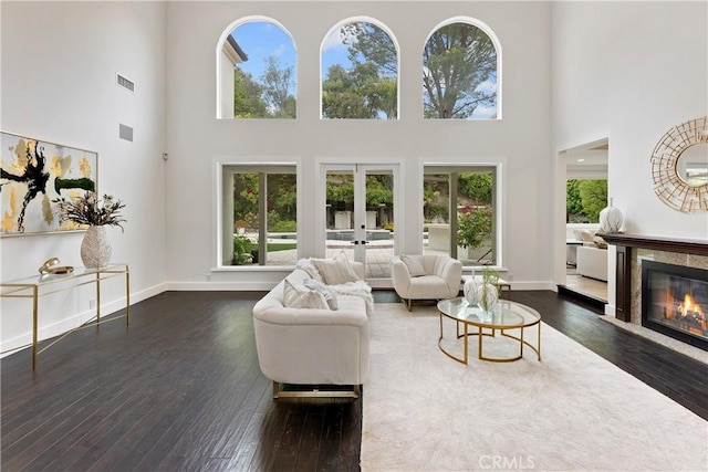 living room with french doors, visible vents, a high ceiling, and wood-type flooring