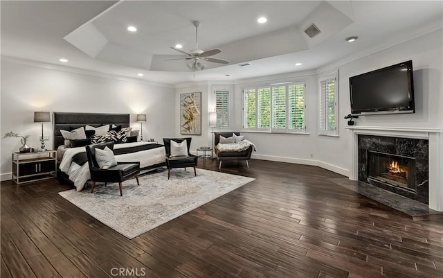 bedroom with a tray ceiling, a fireplace, and ornamental molding