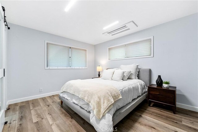 bedroom featuring a barn door, wood finished floors, and baseboards