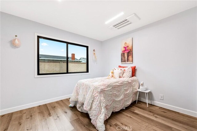 bedroom with visible vents, baseboards, and wood finished floors