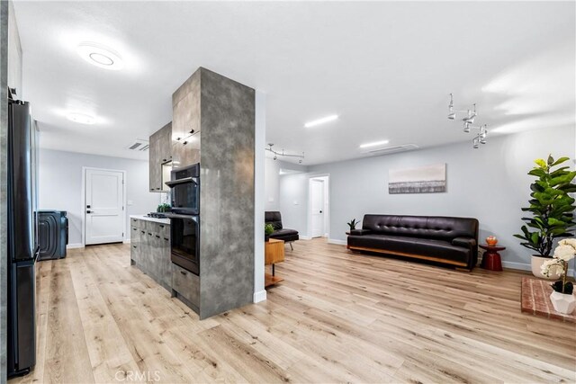 kitchen with light wood-type flooring, black appliances, baseboards, and open floor plan