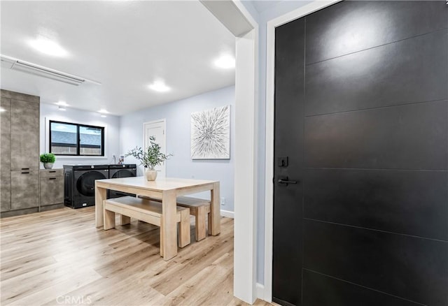 dining space with baseboards, a fireplace, light wood-style flooring, and washing machine and clothes dryer