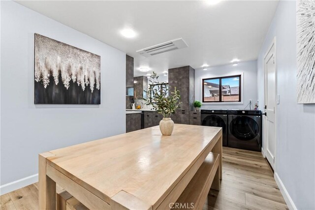 dining room with light wood-type flooring, washing machine and dryer, visible vents, and baseboards