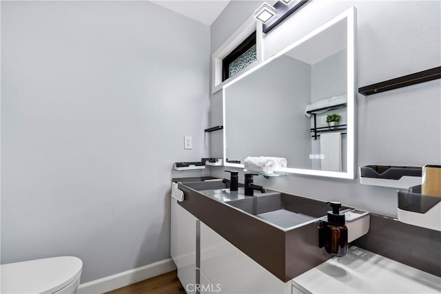 bathroom with baseboards, vanity, toilet, and wood finished floors