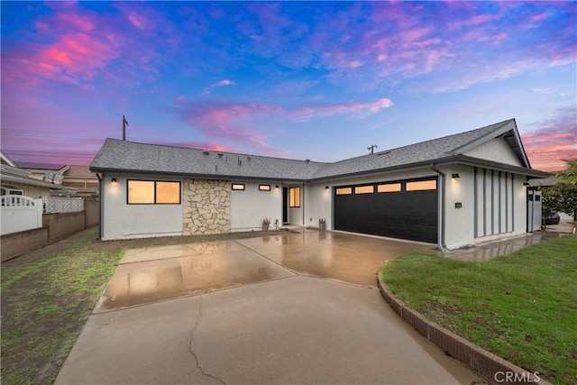 view of front of property with concrete driveway, fence, an attached garage, and stucco siding