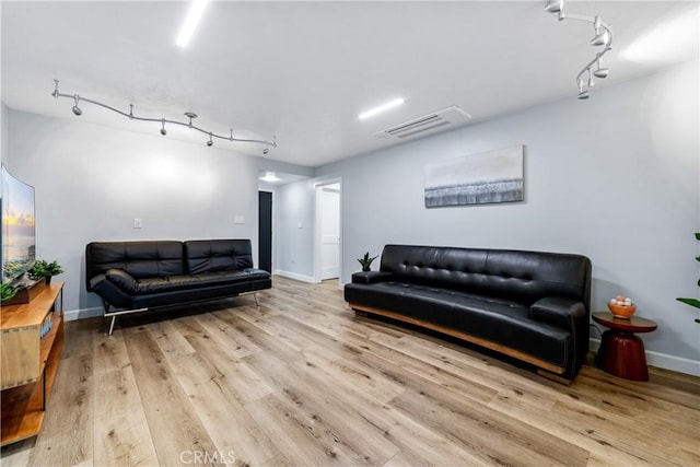 living area with track lighting, wood finished floors, visible vents, and baseboards