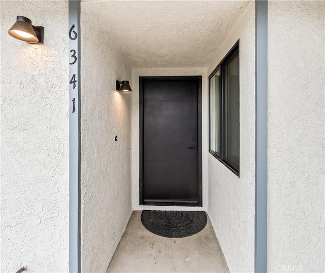 doorway to property featuring stucco siding