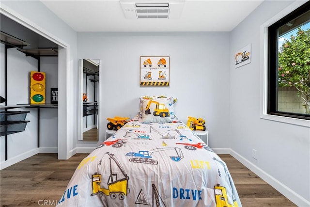 bedroom featuring visible vents, baseboards, and wood finished floors