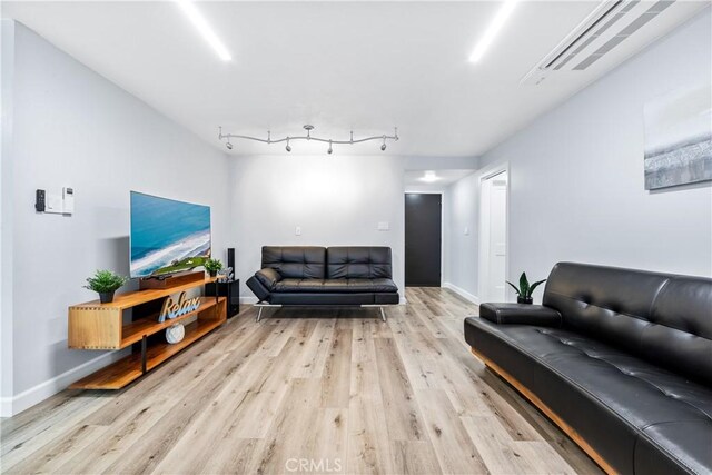 living room with rail lighting, light wood-style flooring, and baseboards