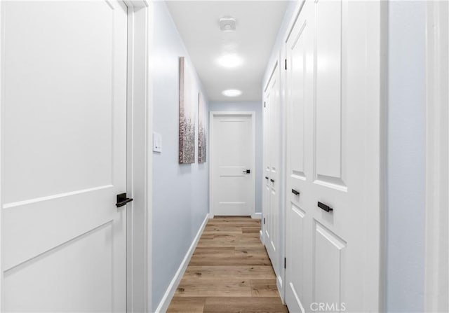 hall with baseboards and light wood finished floors