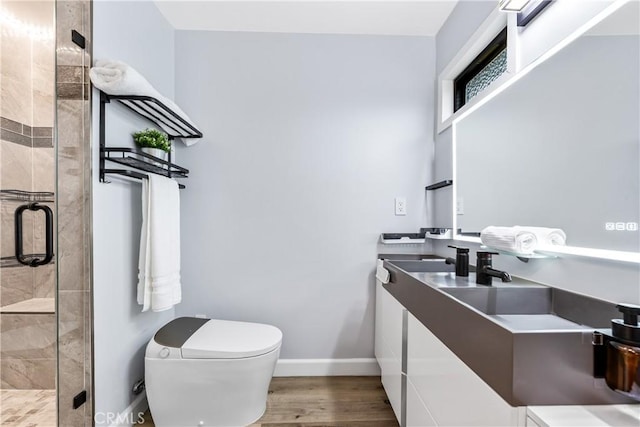 bathroom with toilet, wood finished floors, vanity, baseboards, and a stall shower