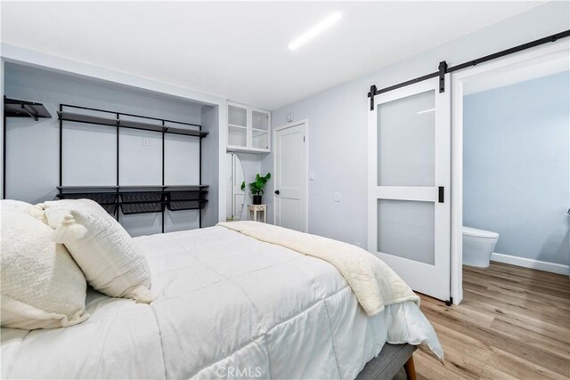 bedroom featuring a barn door, wood finished floors, and baseboards