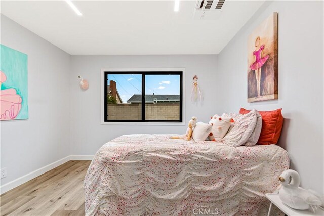 bedroom with visible vents, baseboards, and wood finished floors