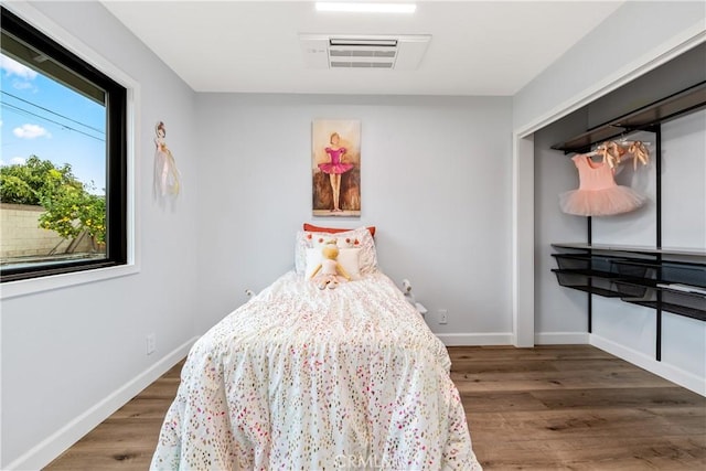 bedroom featuring wood finished floors, visible vents, and baseboards