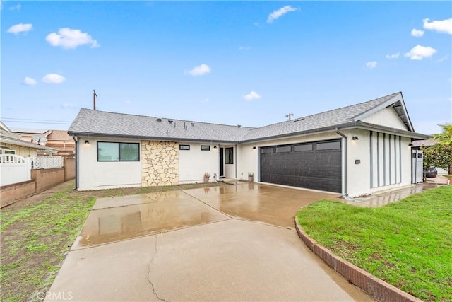 ranch-style home featuring a shingled roof, concrete driveway, an attached garage, a front yard, and fence