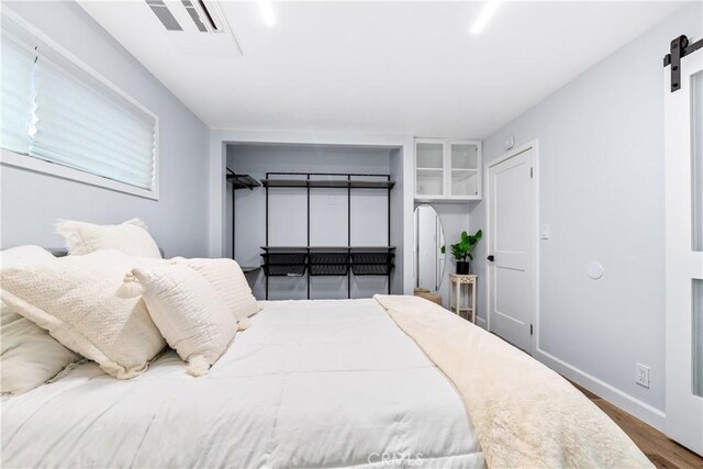 bedroom featuring a barn door, baseboards, and wood finished floors